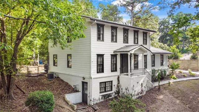 a view of a white house with large windows and a small yard