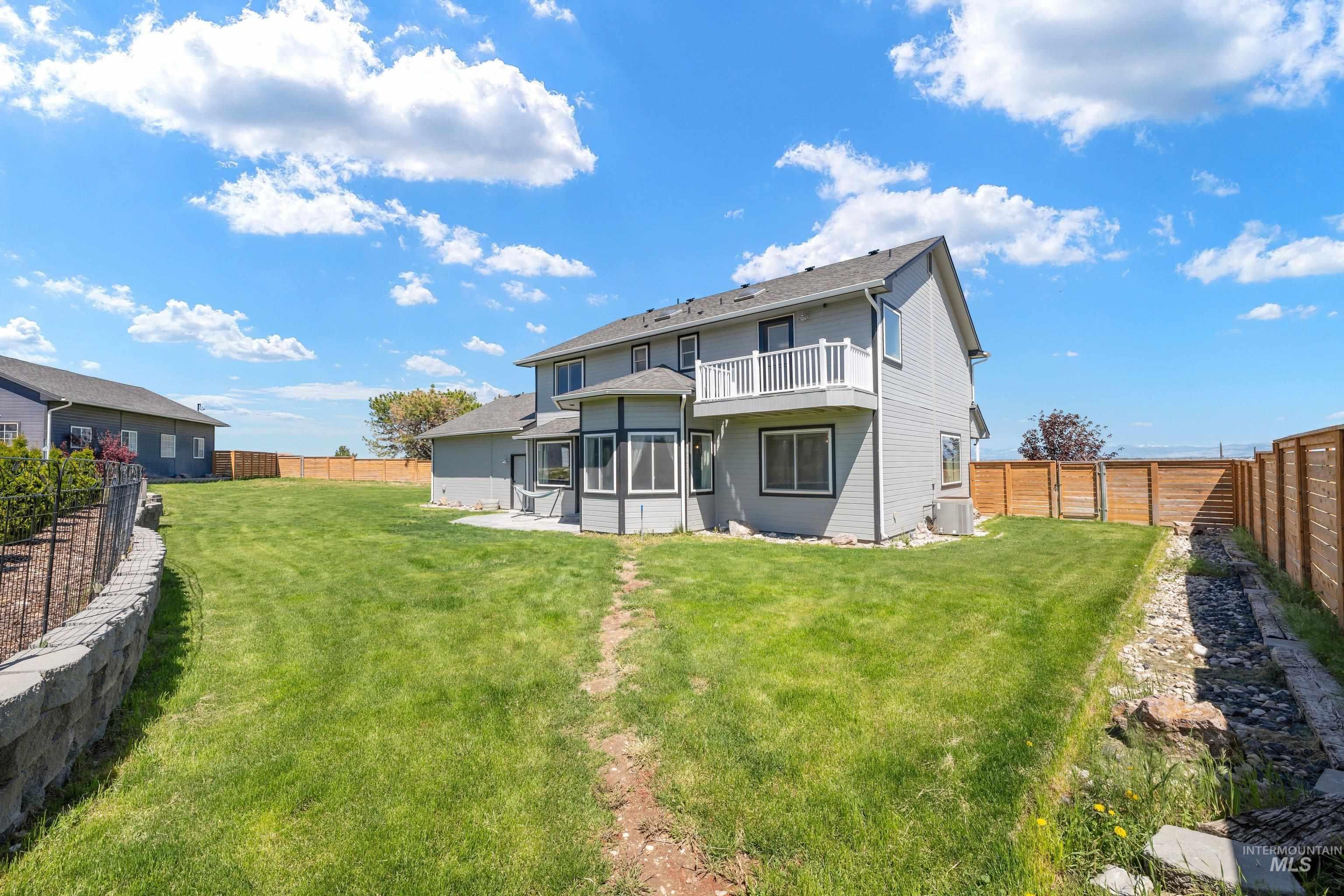 7657 Track Road Nampa, ID 83686 - Photo 38 of 49 Expansive backyard featuring a manicured lawn, a retaining wall, and a wooden privacy fence