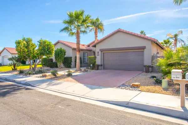 a view of a house with palm trees and a small yard