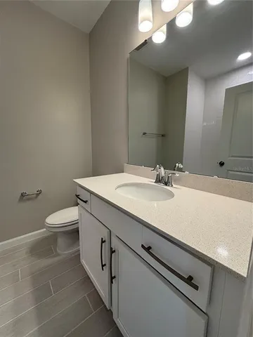 a bathroom with a granite countertop sink a toilet and a mirror