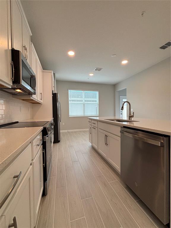 660 Pothos Street Apopka, FL 32703 - Photo 10 of 32 a kitchen with stainless steel appliances a sink dishwasher a microwave oven and a stove with wooden floor