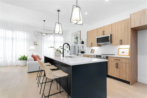 a kitchen with stainless steel appliances a sink a kitchen island with wooden cabinets and wooden floor