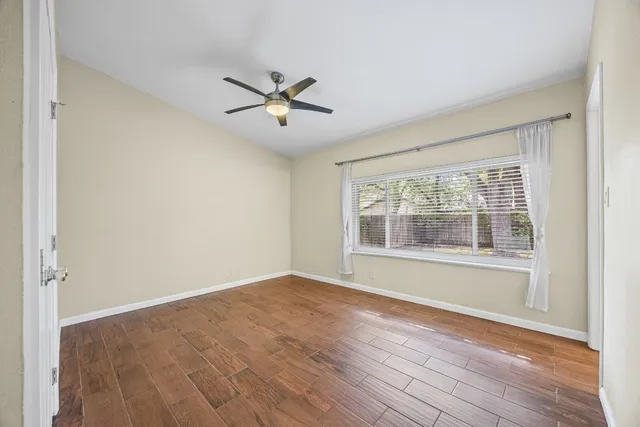 a view of empty room with wooden floor and fan