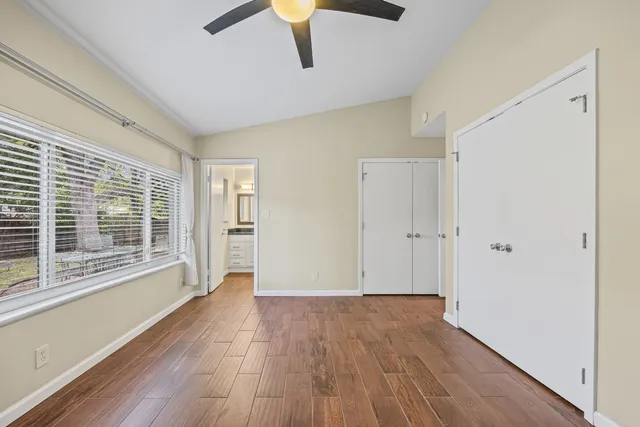 a view of an empty room with wooden floor and a window