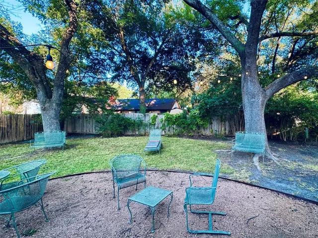 a view of backyard with table and chairs plants and large trees