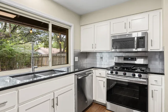a kitchen with granite countertop a stove a sink and a microwave