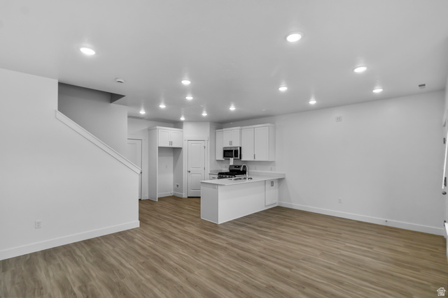 3014 South 265th Street West Logan, UT 84321 - Photo 4 of 25 Open-concept living area featuring wood-finish flooring, recessed lighting, and a white kitchen with a built-in microwave and stainless steel sink