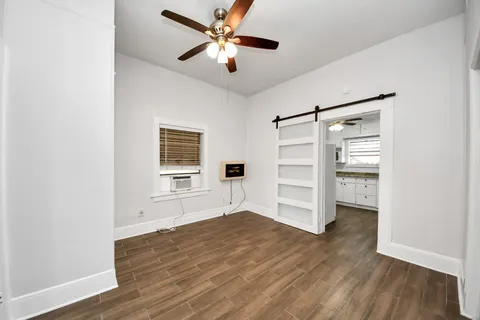a view of an empty room with a window and wooden floor