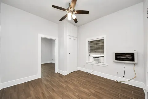 a view of empty room with wooden floor and fan