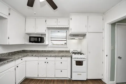 a kitchen with granite countertop white cabinets and white appliances