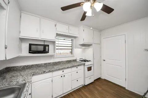 a kitchen with granite countertop cabinets stainless steel appliances and a wooden floor