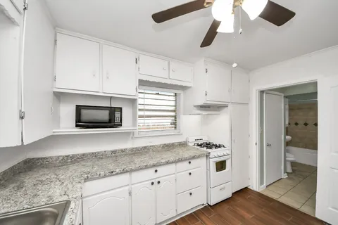 a kitchen with stainless steel appliances granite countertop a stove a microwave and white cabinets