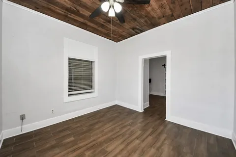 a view of an empty room with wooden floor and a chandelier fan