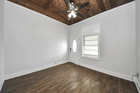 an empty room with wooden floor chandelier fan and windows