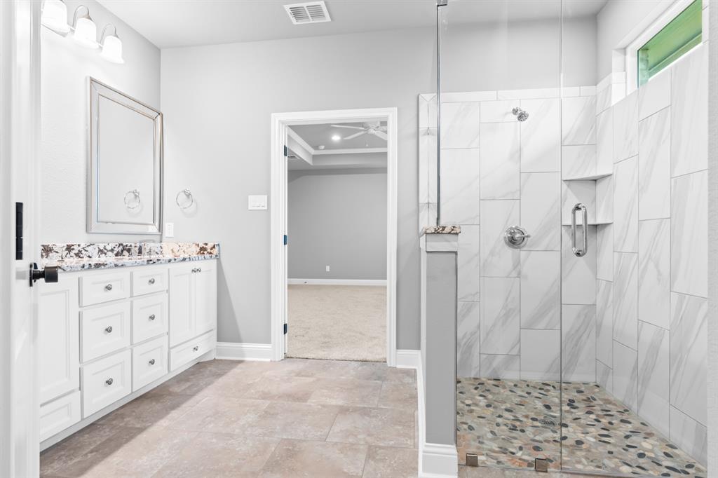 120 Water View Lane Robinson, TX 76706 - Photo 18 of 34 Master bathroom featuring vanity, ceiling fan, and tiled shower.