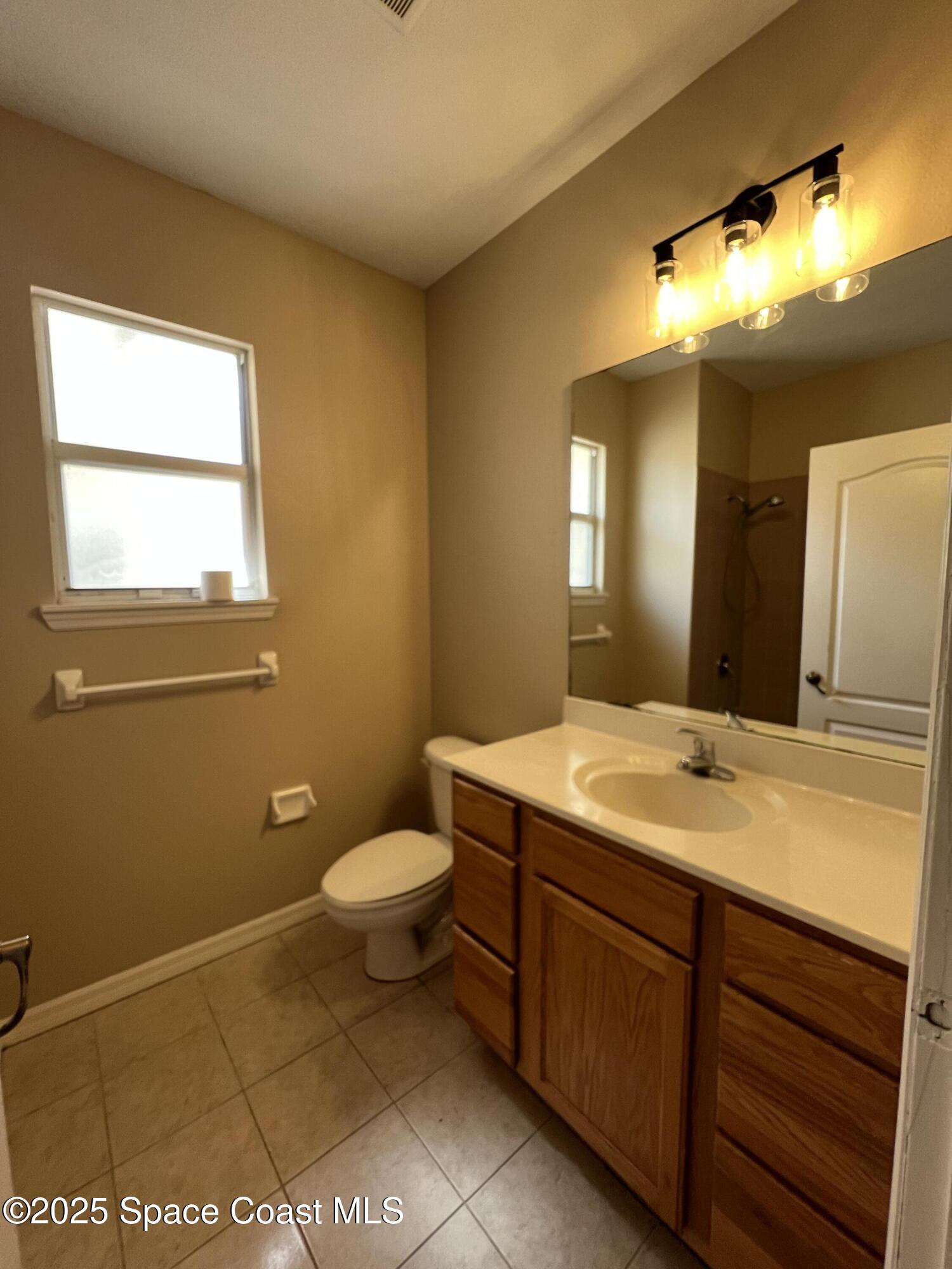 1040 Venetian Drive, Unit 203 Melbourne, FL 32904 - Photo 18 of 23 a bathroom with a sink a toilet and mirror