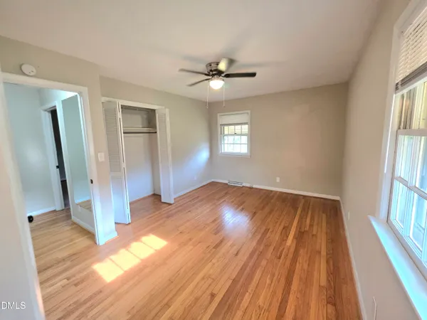 a view of empty room with wooden floor and fan