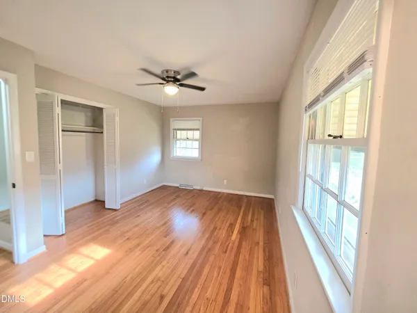 a view of empty room with wooden floor and fan