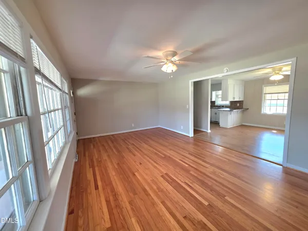 a view of an empty room with wooden floor and a window
