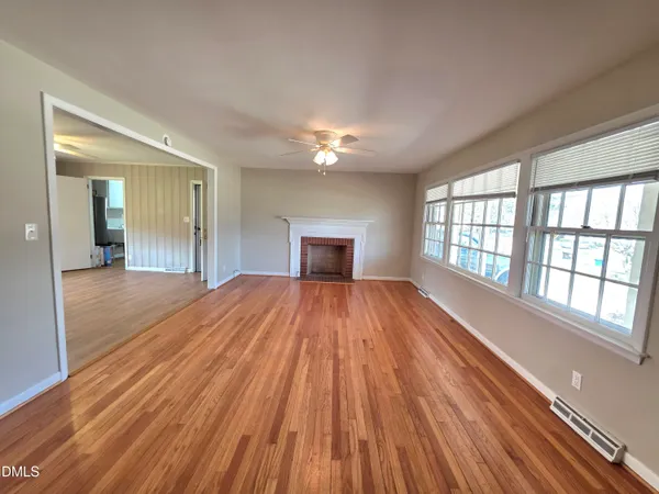 a view of an empty room with wooden floor and a window