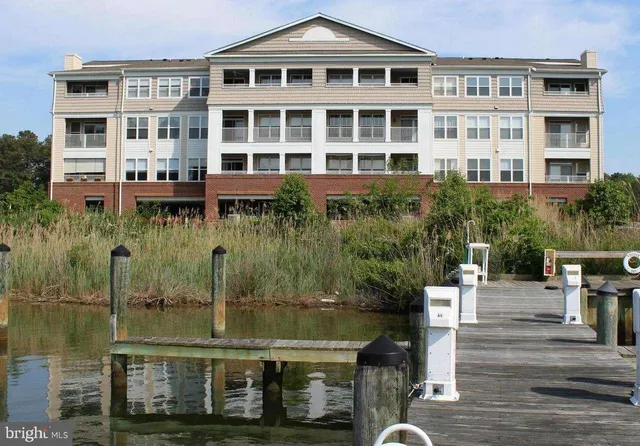 a front view of a building with glass windows and plants