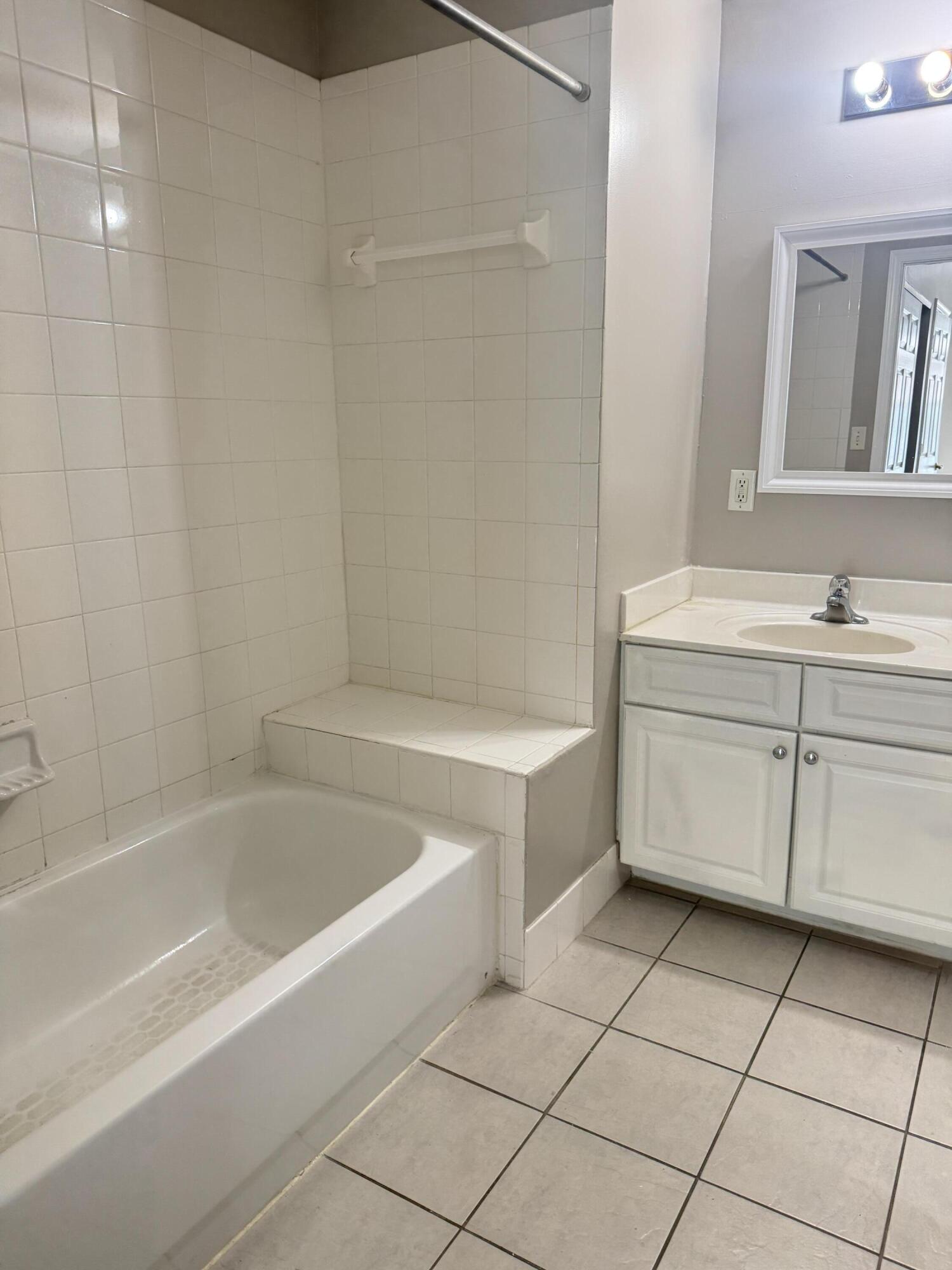 1203 Town Center Drive, Unit 306 Jupiter, FL 33458 - Photo 9 of 21 a bathroom with a bathtub sink vanity and mirror