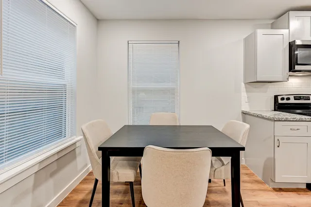 a kitchen with stainless steel appliances a dining table chairs and granite top
