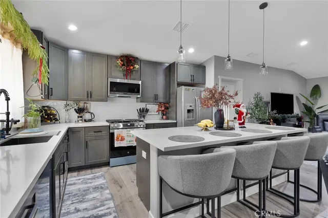 a kitchen with stainless steel appliances granite countertop a sink dishwasher a stove a refrigerator a kitchen island with chairs and white cabinets
