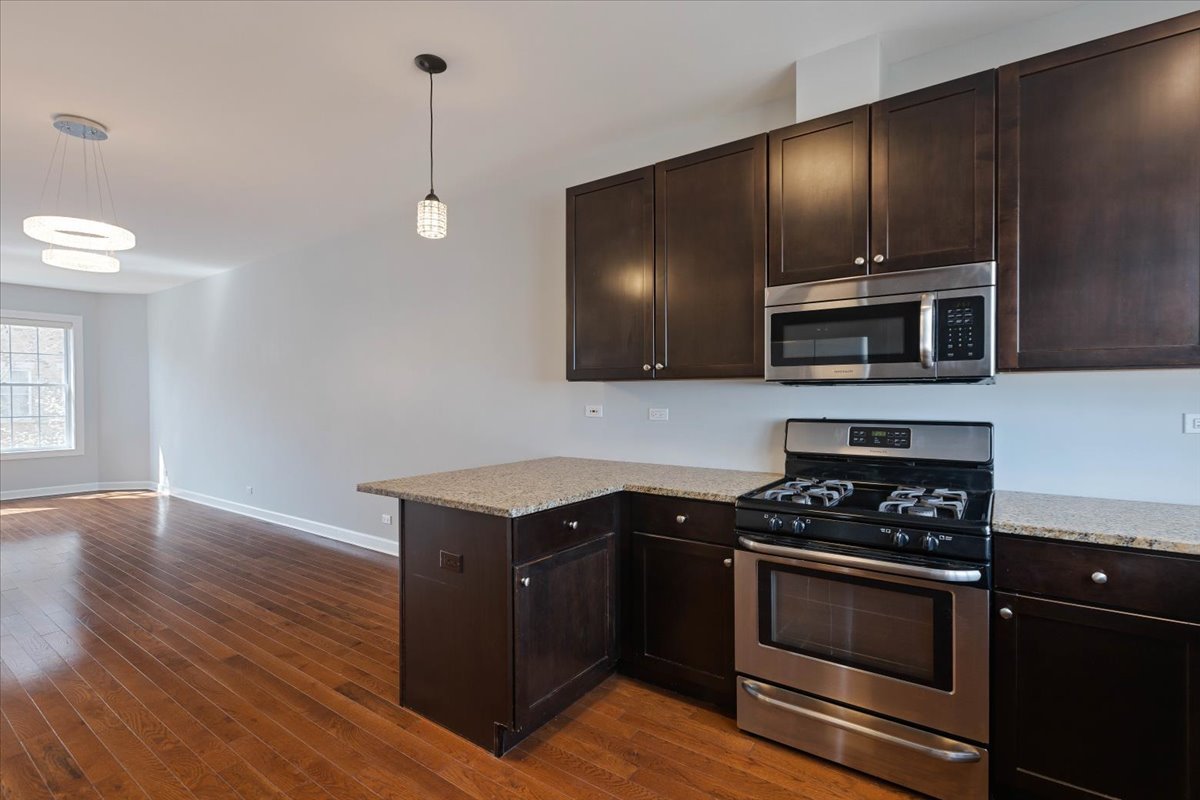 1669 Church Street Evanston, IL 60201 - Photo 9 of 31 a kitchen with granite countertop a stove and a wooden floor