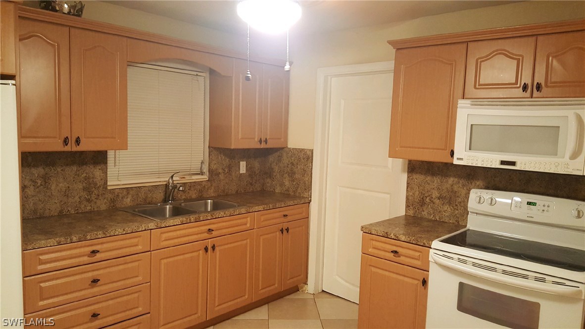 1003 East Penn Road Lehigh Acres, FL 33936 - Photo 11 of 12 a kitchen with granite countertop white cabinets and white appliances