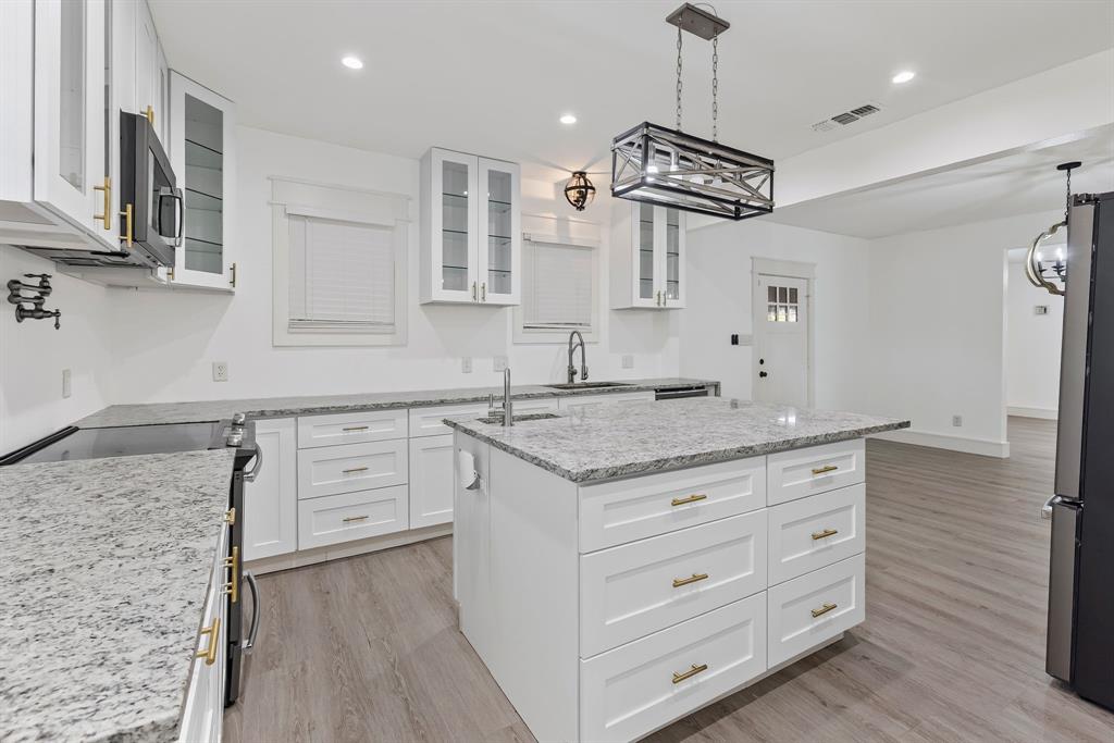 509 Maple Street Commerce, TX 75428 - Photo 14 of 36 a kitchen with granite countertop cabinets a sink a window and stainless steel appliances