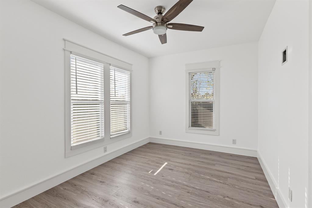 509 Maple Street Commerce, TX 75428 - Photo 27 of 36 an empty room with wooden floor ceiling fan and windows