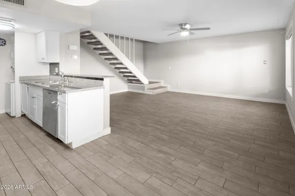an empty room with wooden floor and staircase