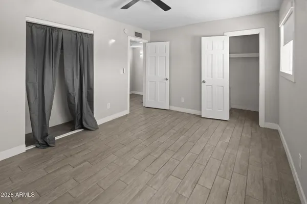 an empty room with wooden floor and closet area