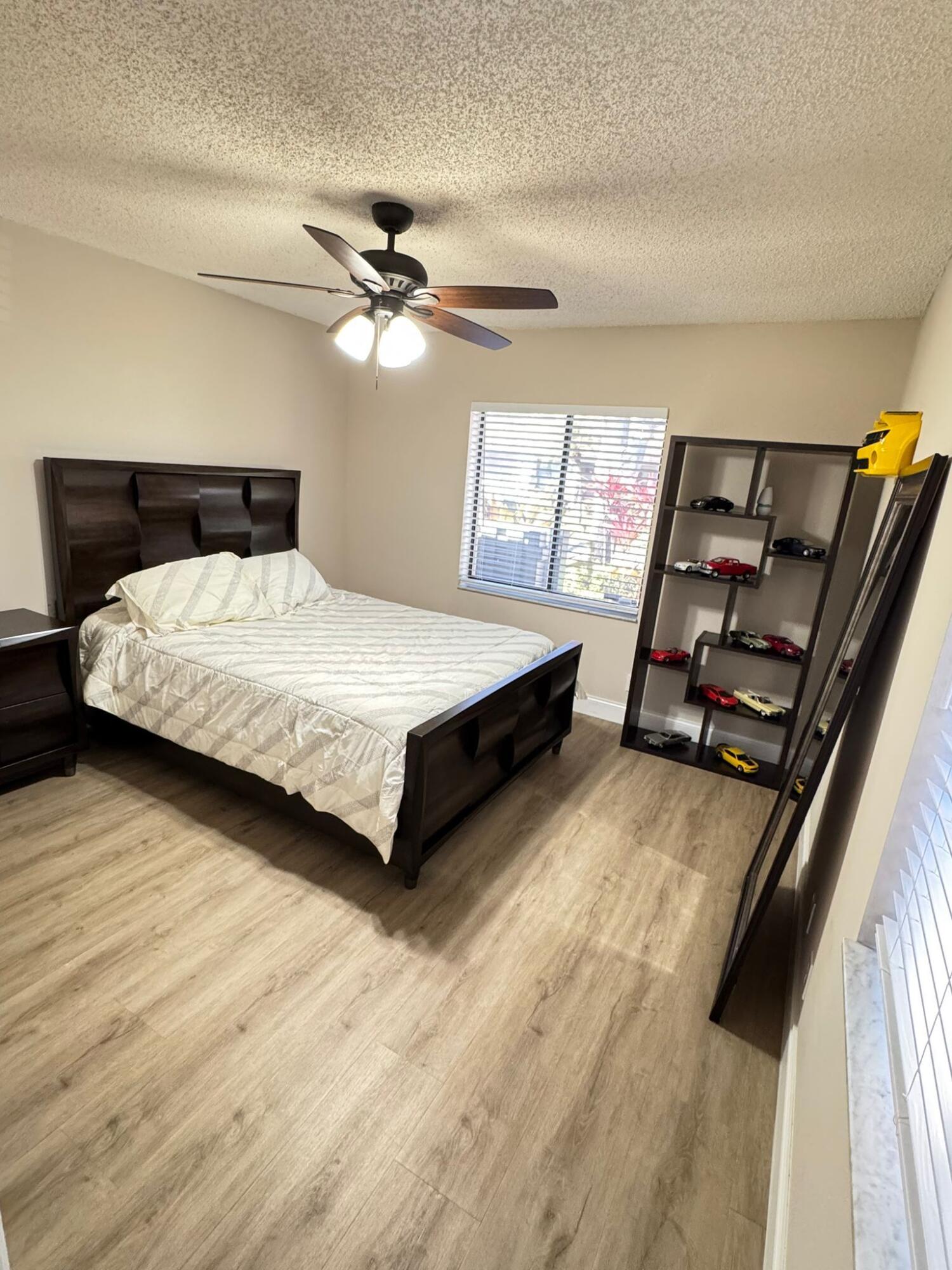 18560 Sunburst Lane, Unit D Boca Raton, FL 33496 - Photo 12 of 28 a bedroom with a bed and wooden floor