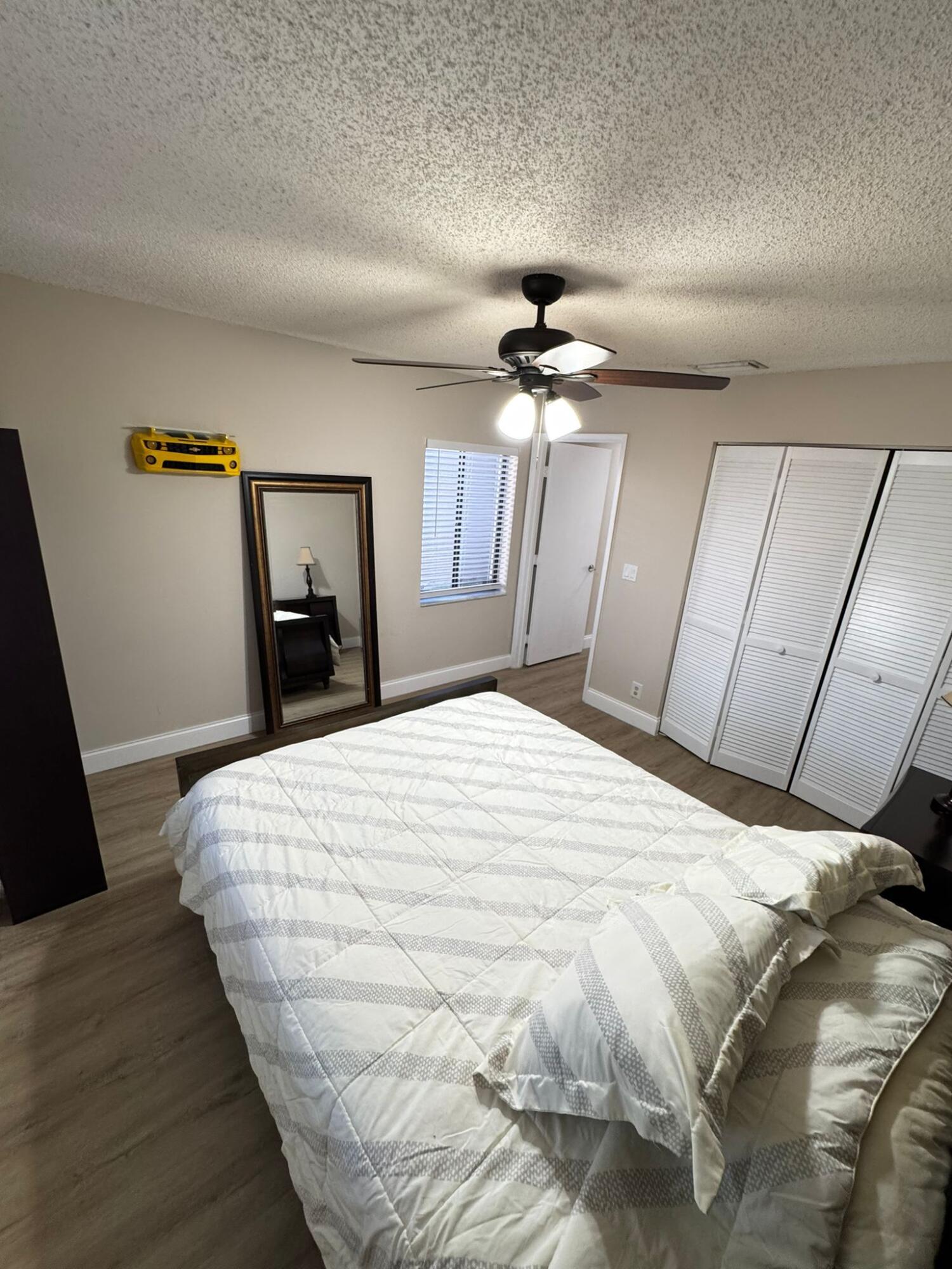 18560 Sunburst Lane, Unit D Boca Raton, FL 33496 - Photo 13 of 28 a bedroom with a bed and a mirror