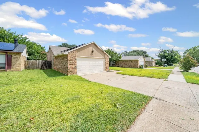 a view of a house with a yard and large tree