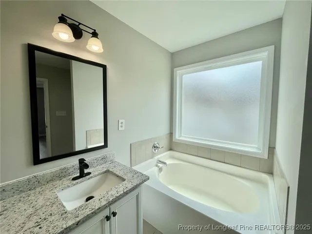 a bathroom with a granite countertop tub sink and mirror