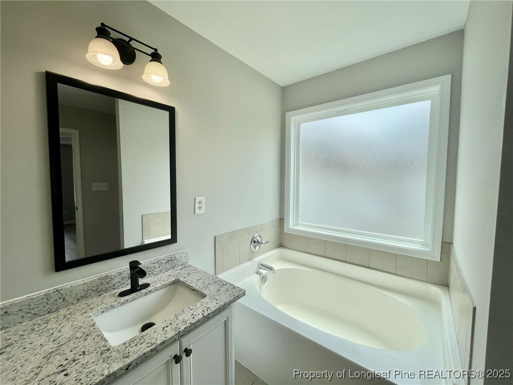 216 Cobblestone Drive Spring Lake, NC 28390 - Photo 13 of 30 a bathroom with a granite countertop tub sink and mirror