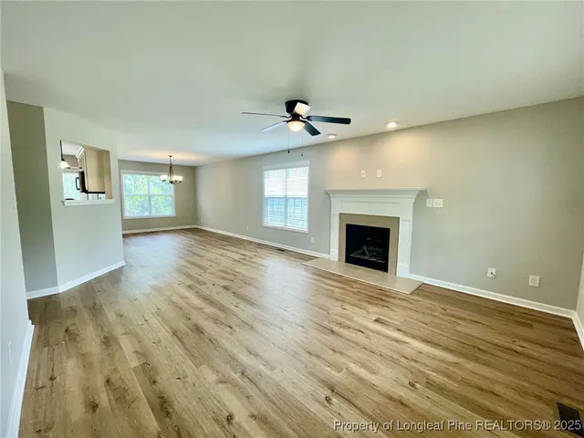 a view of an empty room with wooden floor and a fireplace