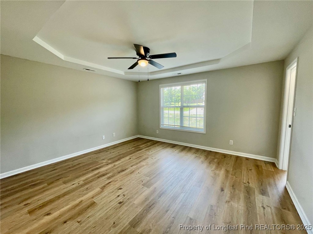 216 Cobblestone Drive Spring Lake, NC 28390 - Photo 8 of 30 an empty room with wooden floor ceiling fan and windows