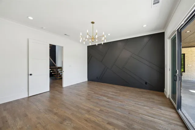 a view of an empty room with wooden floor and closet area