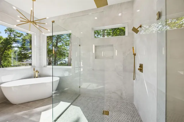 a spacious bathroom with a bathtub a shower and a chandelier