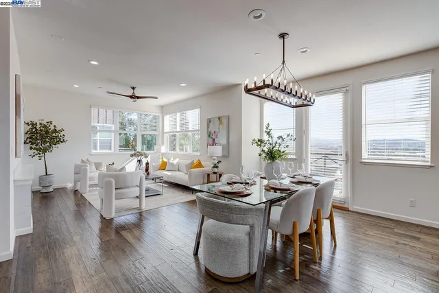 a dining room with wooden floor a chandelier a glass table and chairs