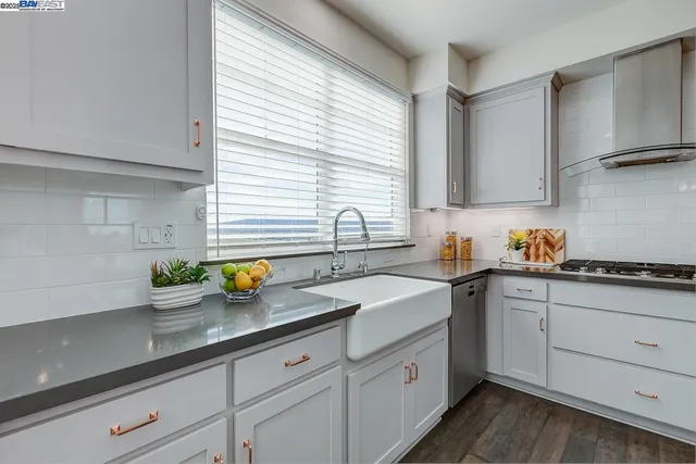 a kitchen with stainless steel appliances white cabinets a sink a stove and a window