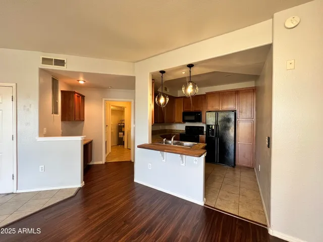 a kitchen view with stainless steel appliances wooden floor and living room view