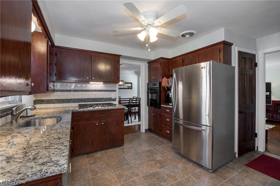 1170 Roland Road Lyndhurst, OH 44124 - Photo 8 of 36 Kitchen with ceiling fan, sink, light stone countertops, backsplash, and stainless steel appliances