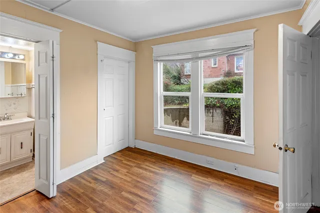 a view of an empty room with wooden floor and a window