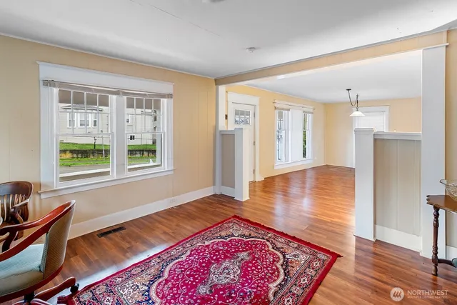 a view of an empty room with window and wooden floor