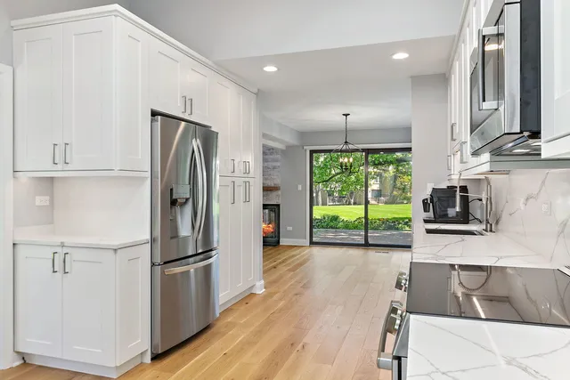 a kitchen with kitchen island granite countertop a refrigerator oven a sink and wooden floors